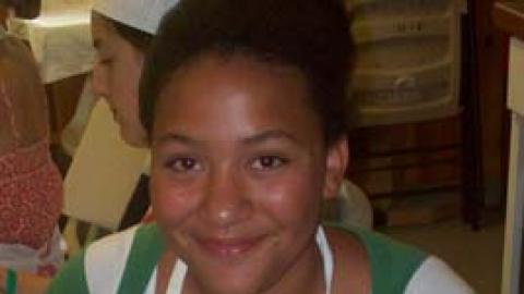 Smiling camper holds a culinary creation. 