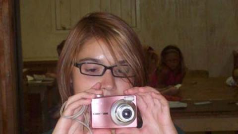 counselor holding a camera with youth in background.