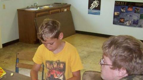 Campers attaching parachute to nose cone of rocket kit.