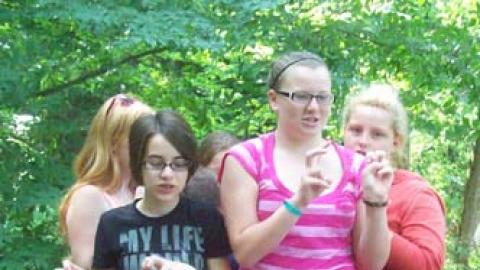 group of youth standing on a ropes course platform singing the beaver song.