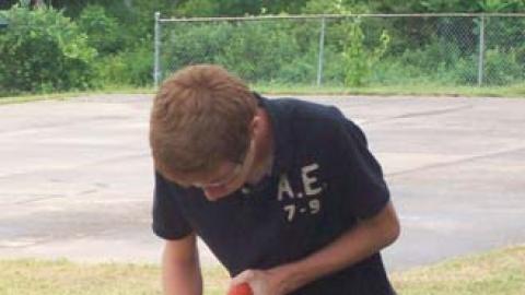 Camper sawing a board outside. 