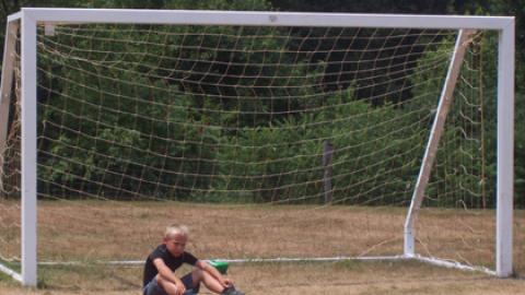 youth sitting in front of a soccer goal.