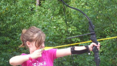 young lady draws her bow and prepares to fire.