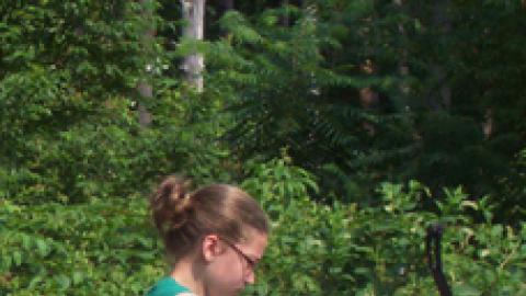 Youth drawing bow on archery range.