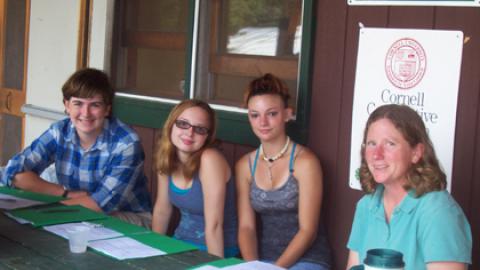 Director sitting with three teens on porch of dining hall.
