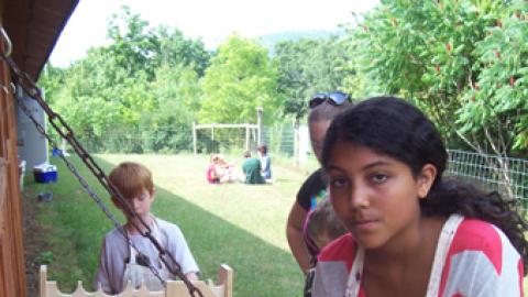 Youth at painting station outside with wooden bookshelf.