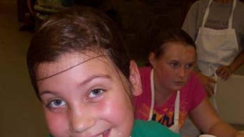 youth displaying a parfait they made while giving a thumbs up.