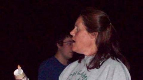 Camp staff holds a candle. 
