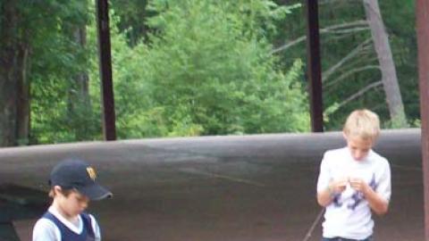 Campers play with fishing poles and bait the hooks. 