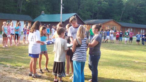 Campers work together to fold the 4-H and American flags while the rest of camp looks on.