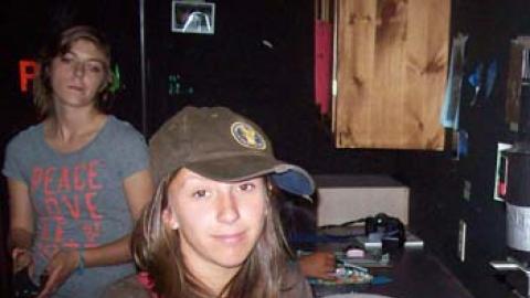 youth leaning on counter and smiling at the camera in darkroom with counselor in background.