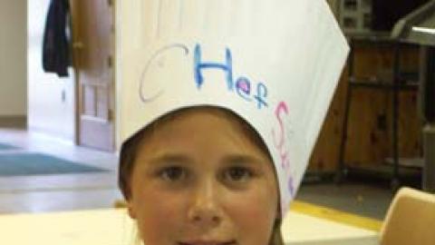young chef displays baked potato creation with added veggies.