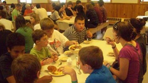 Campers and counselors seated together for a family style meal.
