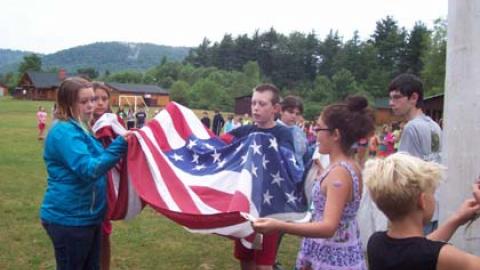 Youth working together to raise the american flag.