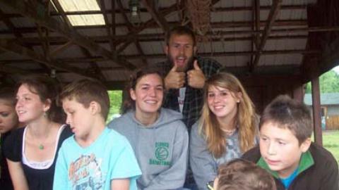 Camp staff sitting at a picnic table together among campers smiling.