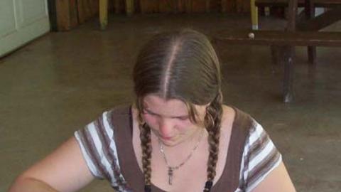 Program Assistant sitting at table putting flowers and leaves on cloth with hammer in flower pounding test.