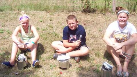 Campers cook outside with coffee can cookers. 