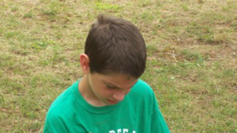 youth using tongs to turn a foil packet over a buddy burner in cookery class