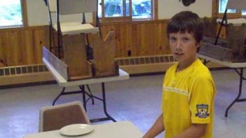 Youth setting plates on an empty table.