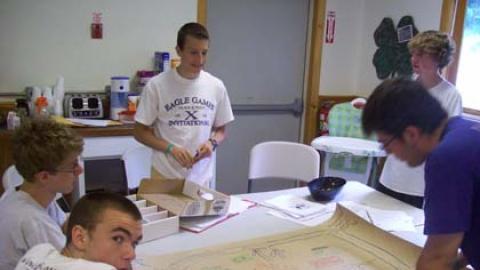 Teens around table drawing a large map of camp.