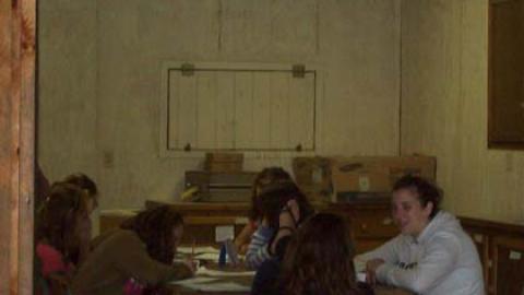 Campers seated around table with counselor.