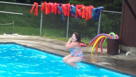Youth doing cannon ball into swimming pool.
