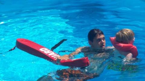 A lifeguard works on swimming lessons with a youth. 