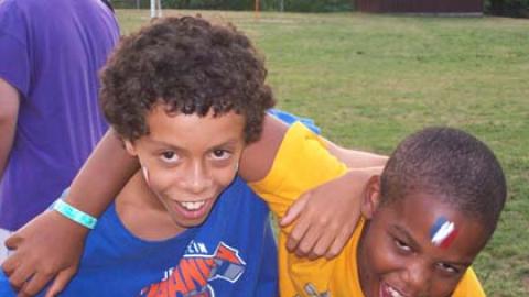 Two youth with paint on their faces smiling with arms around each other.