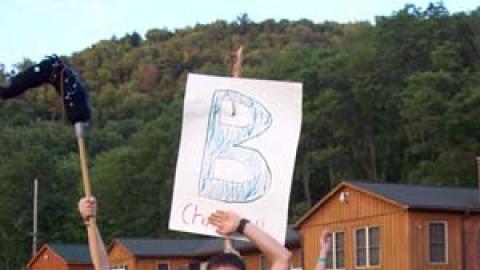 small group of campers and counselors with painted faces  holding a platoon B sign.