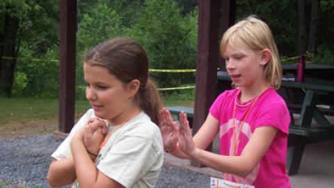 One youth prepares to catch another as they lean back in a trust fall activity.