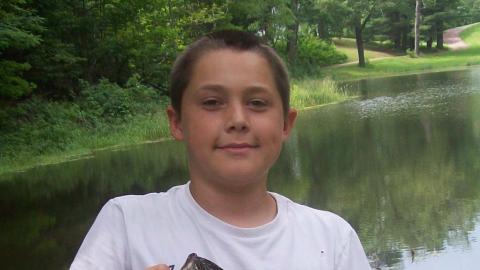 Youth holds up a freshly caught fish. 