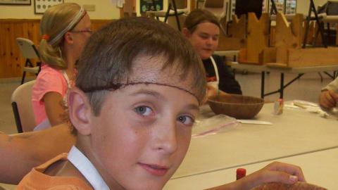 Youth mixing a culinary creation in a wooden bowl during a cooking class. 