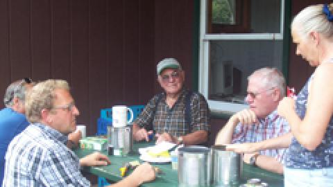 Camp facilities and security staff sitting with camp administrator on back porch of dining hall.