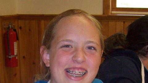 smiling camper mixes food in a wooden bowl 