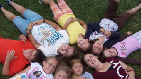 youth laying in the field with their heads together to form a circle.