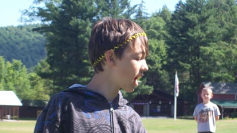 optical illusion where a camper stands in the foreground fist closed out in front and mouth open while another camper stands in the background to apear as though they are being lifted into the first campers mouth to be eaten.