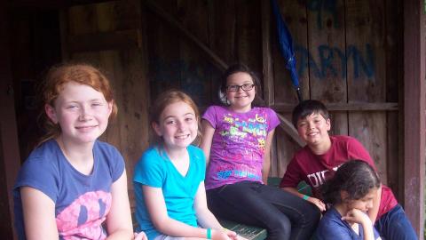 Youth sitting on a picnic table and smiling. 