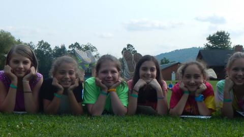 Youth laying on the ground with their hands on their chins and smiling. 