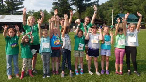 campers stand with their hands in the air with two counselors in the back