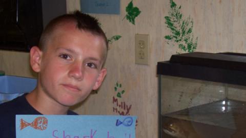 Camper holding up a sign that says "Shark bait caught by: Ben"