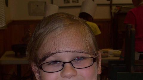 Youth smiling while holding a cooking spoon. 