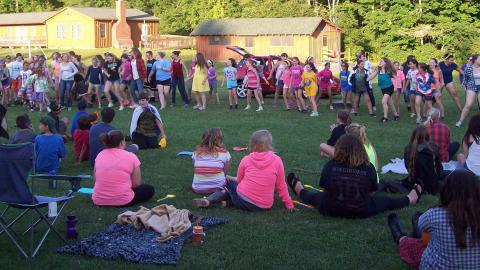 Youth sitting in a circle outside playing a game. 