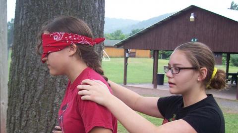 Youth playing a game of trust with one blind folded. 