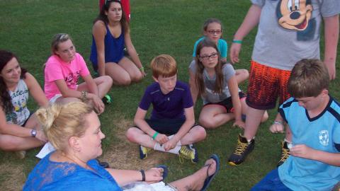 Youth sit in a circle and play a game. 