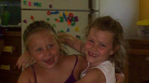 Two smiling youth with their arms wrapped around each other. 