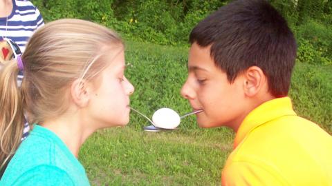 Campers doing a relay race with spoons in their mouths and an egg. 