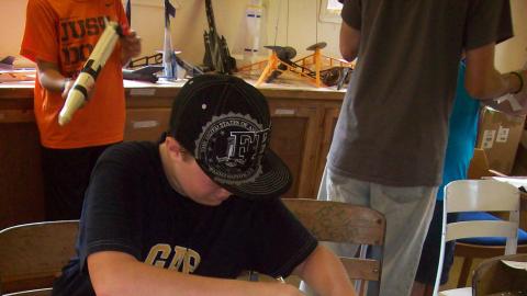 Youth cuts out a piece for a model rocket. 