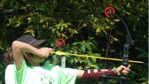 Youth shooting an arrow from a distance. 