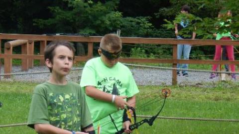 Campers prepare to shoot bow and arrows outside of camp. 