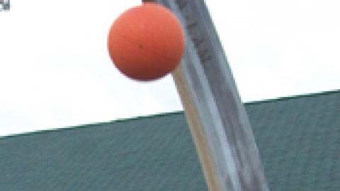 youth jumps with arms extended above their head toward a basketball hoop to make a basket.